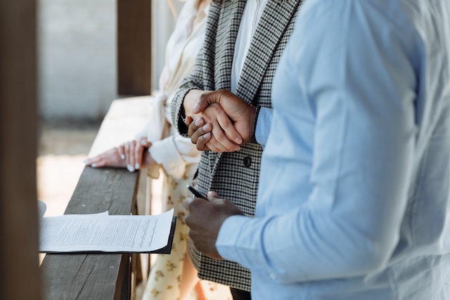 two people shaking hands over a signed contract at a house